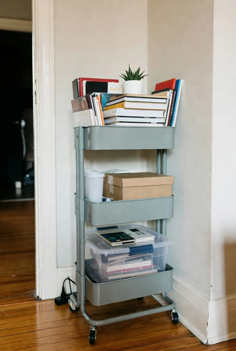 Three-tier rolling storage cart used in a small home, holding kitchen or office supplies, flexible and movable storage solution, clutter-free setup, modern minimalist style, realistic photography