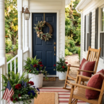 Classic Americana front porch with wood rocking chairs grain sack red pillows striped rug and galvanized planters with red and blue flowers