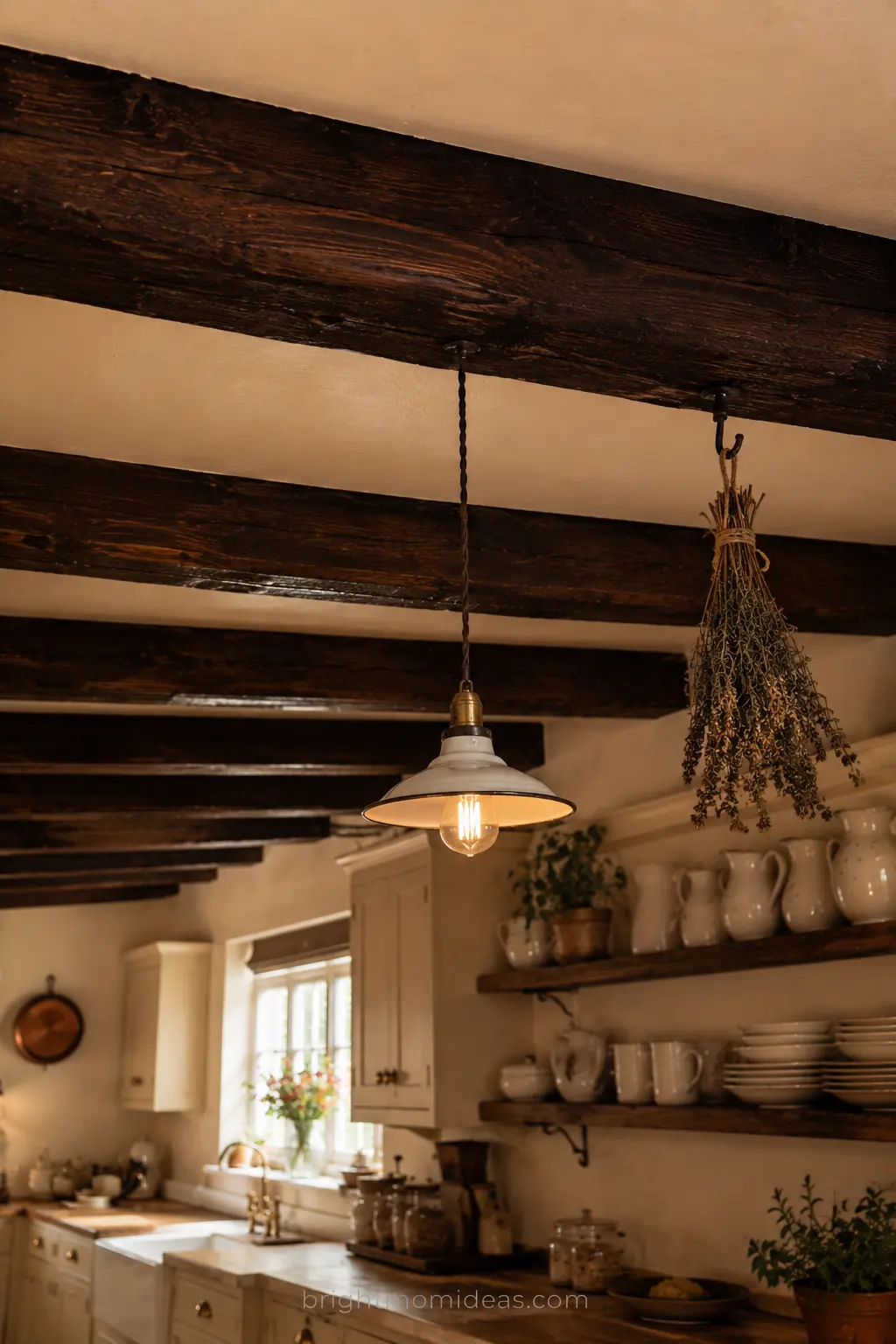 exposed dark walnut wooden ceiling beams
in english cottage kitchen above cream
cabinets white ceramics and warm lighting
creating old world character and warmth