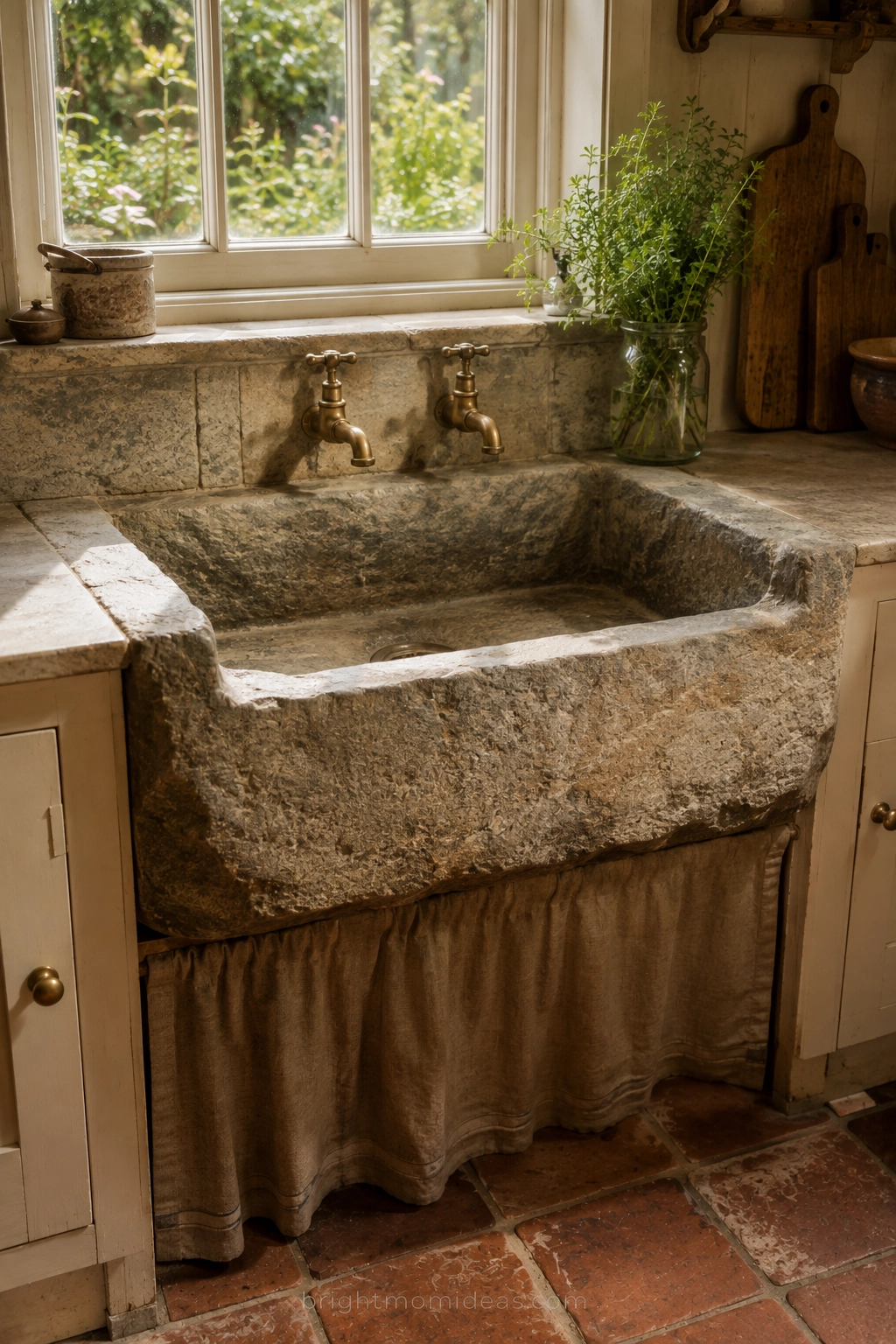 reclaimed stone trough sink in english
cottage kitchen showing weight texture
and old world authenticity of natural
stone material with aged brass fittings